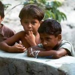 Drei Kinder lehnen an einer Mauer