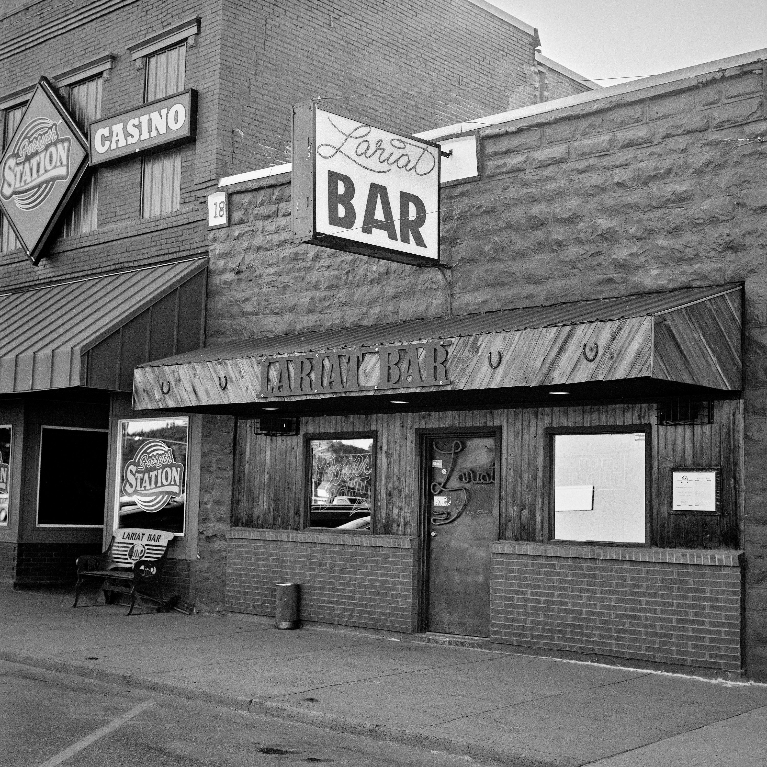 Lariat Bar with vintage neon signage and Forsyth Station casino on small town main street