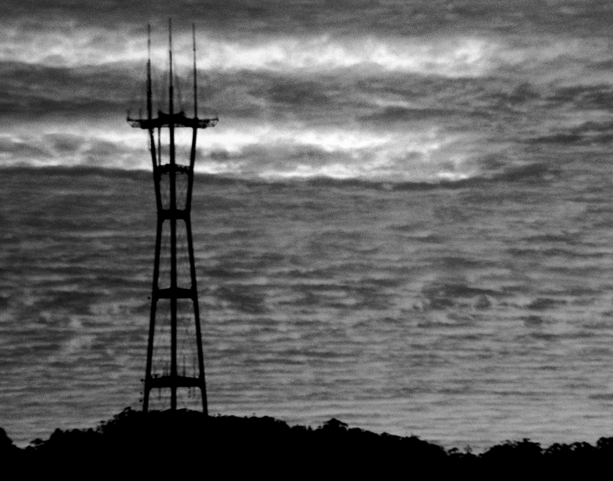 Radio transmission tower silhouetted against stormy ocean horizon with turbulent clouds and dramatic sky