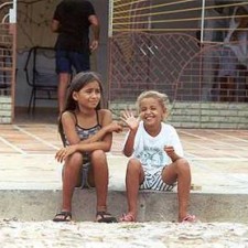 Zwei Kinder sitzen auf einer Stufe, eines winkt