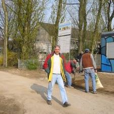 Mann geht auf dem Baugelände, Arbeiter im Hintergrund