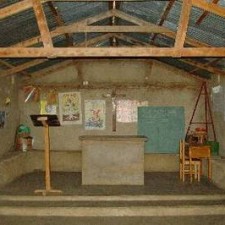 Einfacher Kapellenraum mit Lehmboden, Altar und bunten Wandbildern