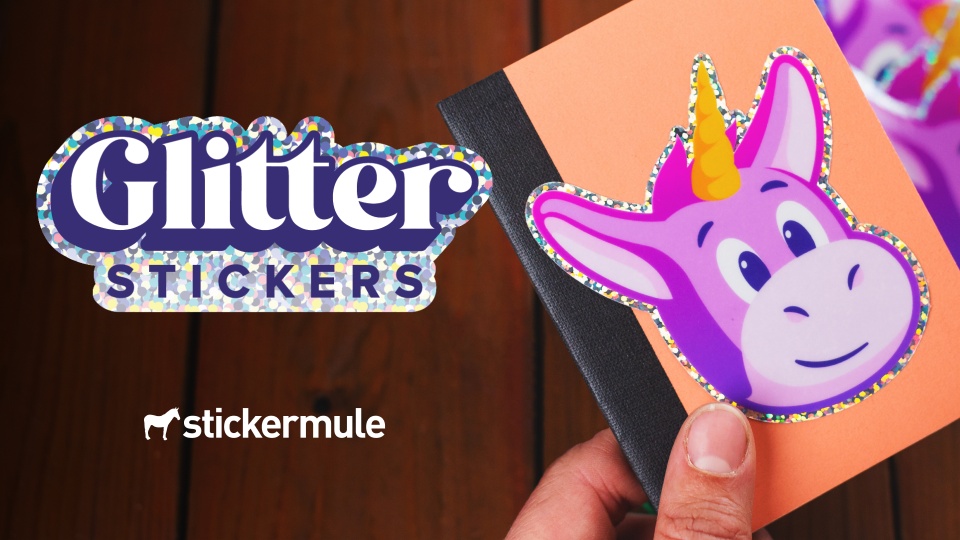 Glitter sticker video thumbnail — hand holding a holographic unicorn sticker on black card