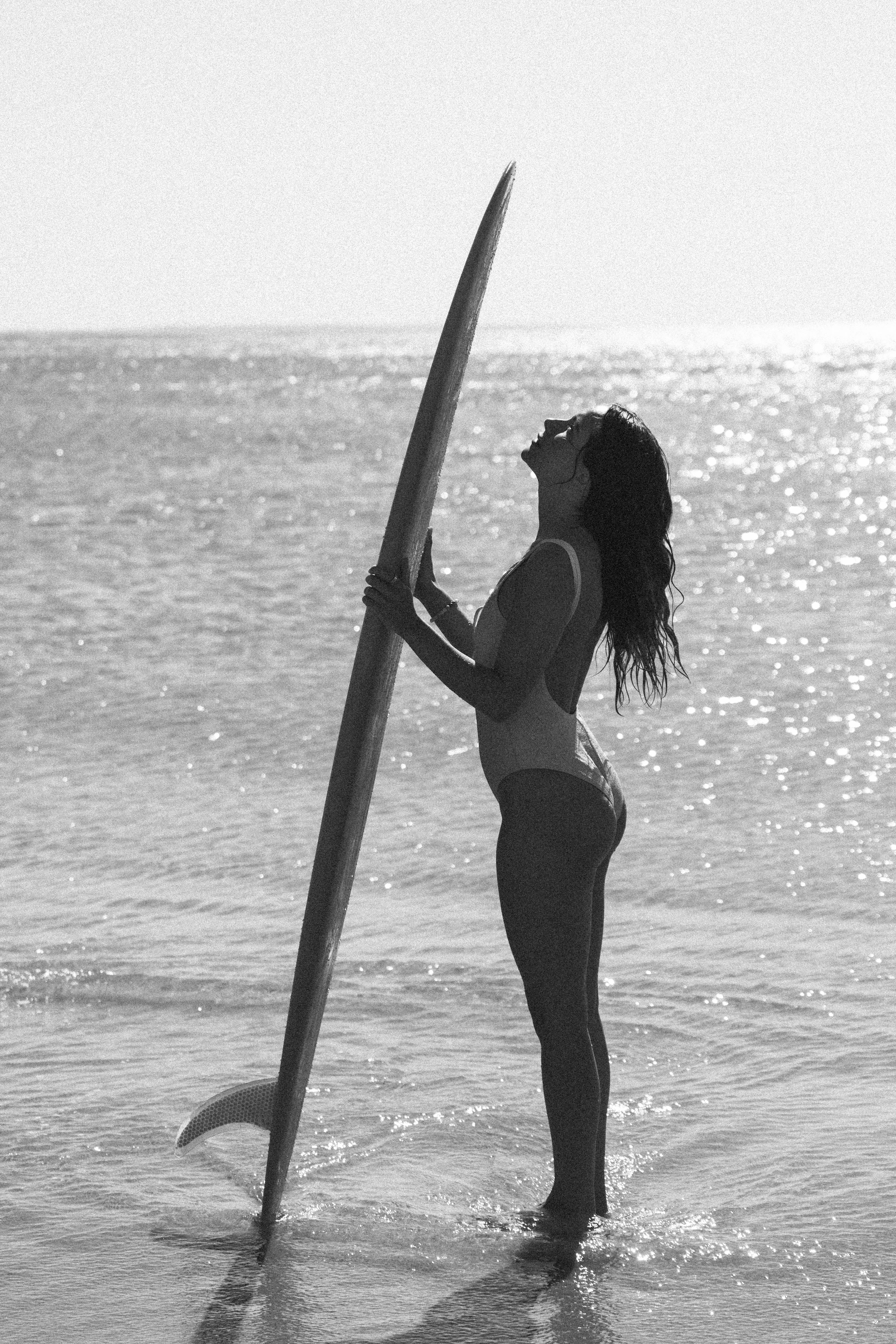 Black and white silhouette holding surfboard in water