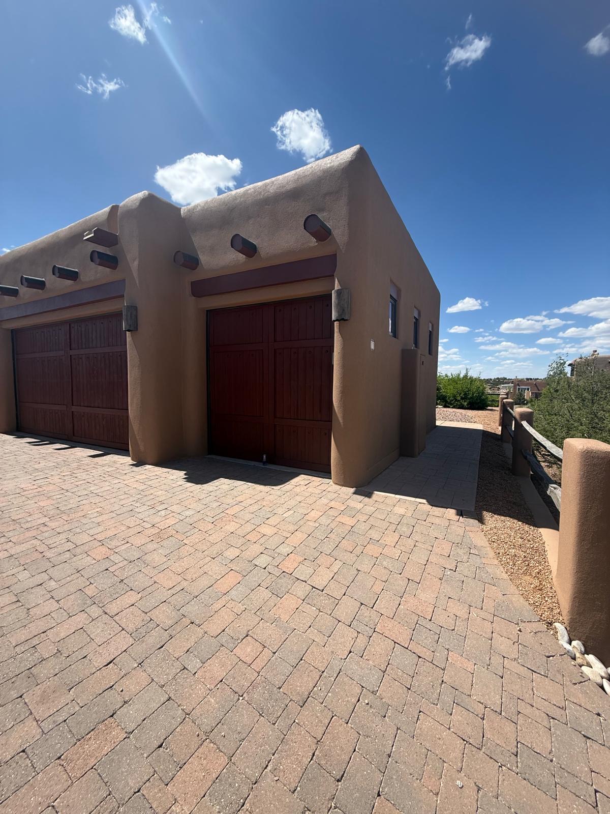 Double garage with adobe stucco exterior and brick driveway