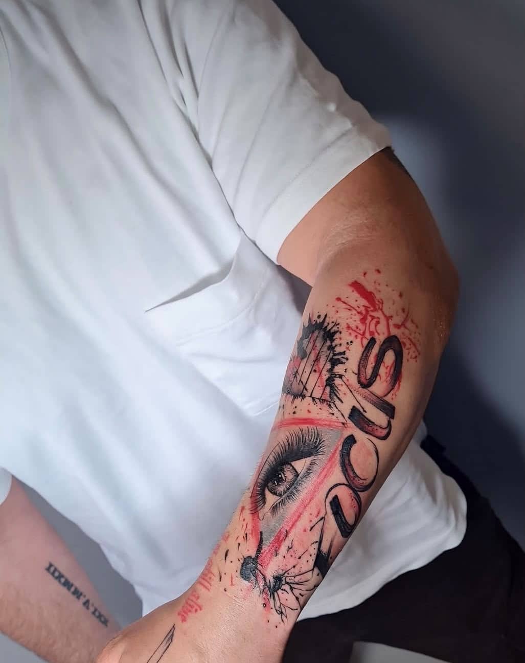 Trash Polka Unterarm mit Auge und Lost-Text, rote Splitter