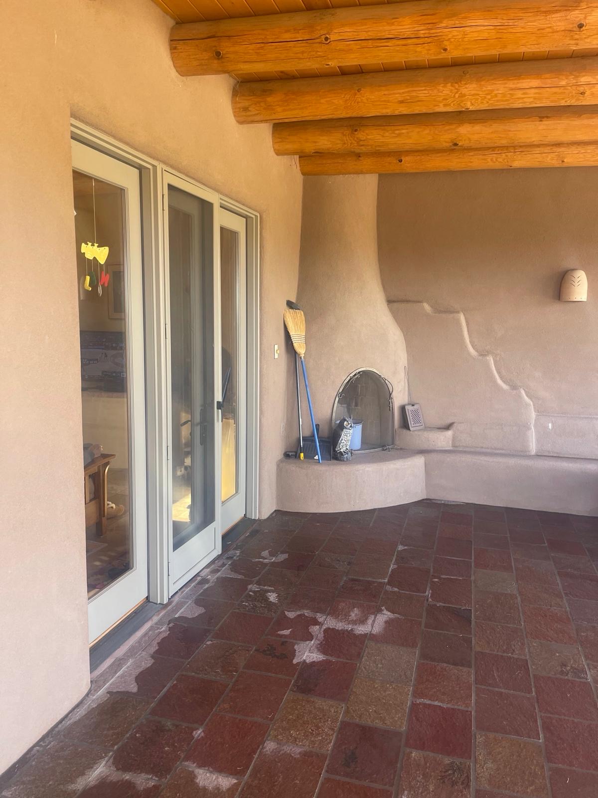 Outdoor kiva fireplace on covered patio with wood beam ceiling