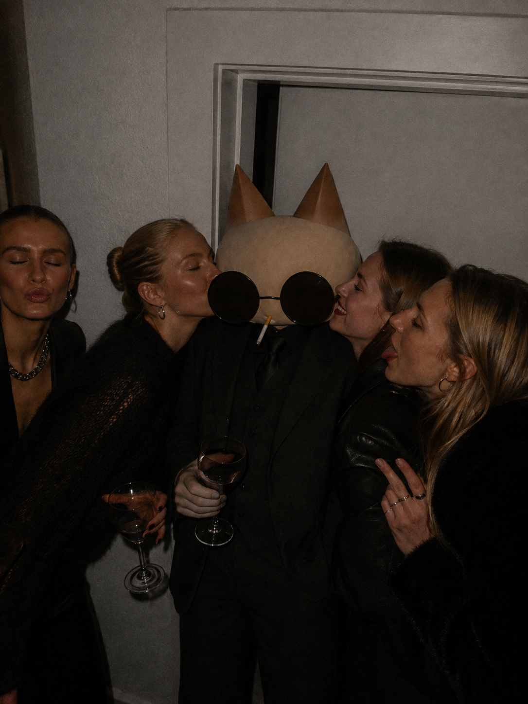 Wisker surrounded by four women at a dark party.
