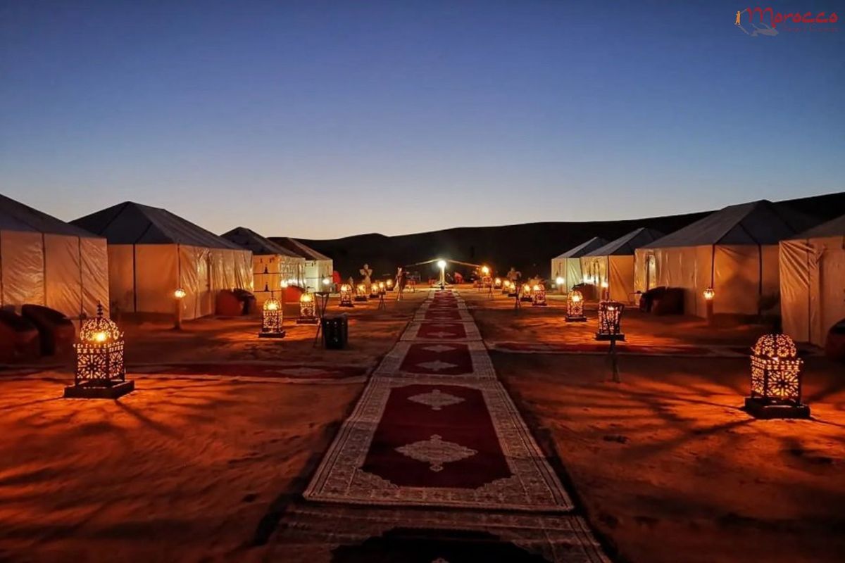 Luxury desert camp at night with illuminated Moroccan tents and ornate lanterns
