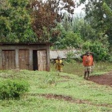Zwei Menschen auf einer grünen Wiese mit traditionellen Holzhütten im Hintergrund