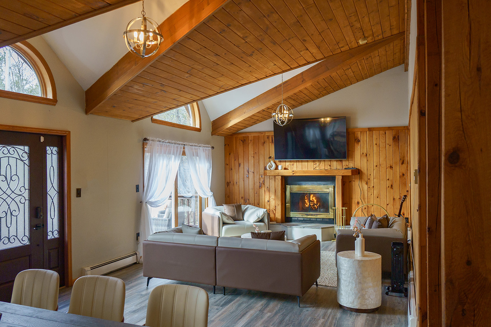 Living room with fireplace, vaulted wooden ceiling and elegant lighting