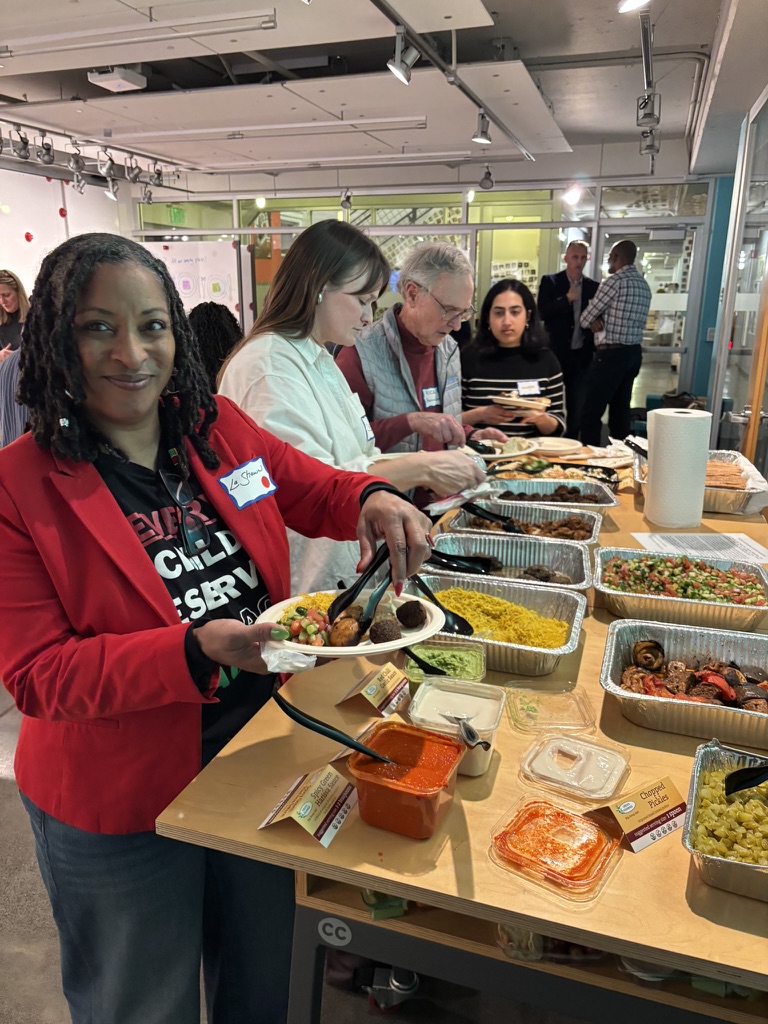 Participant in red Teach For America shirt serving food at the buffet table