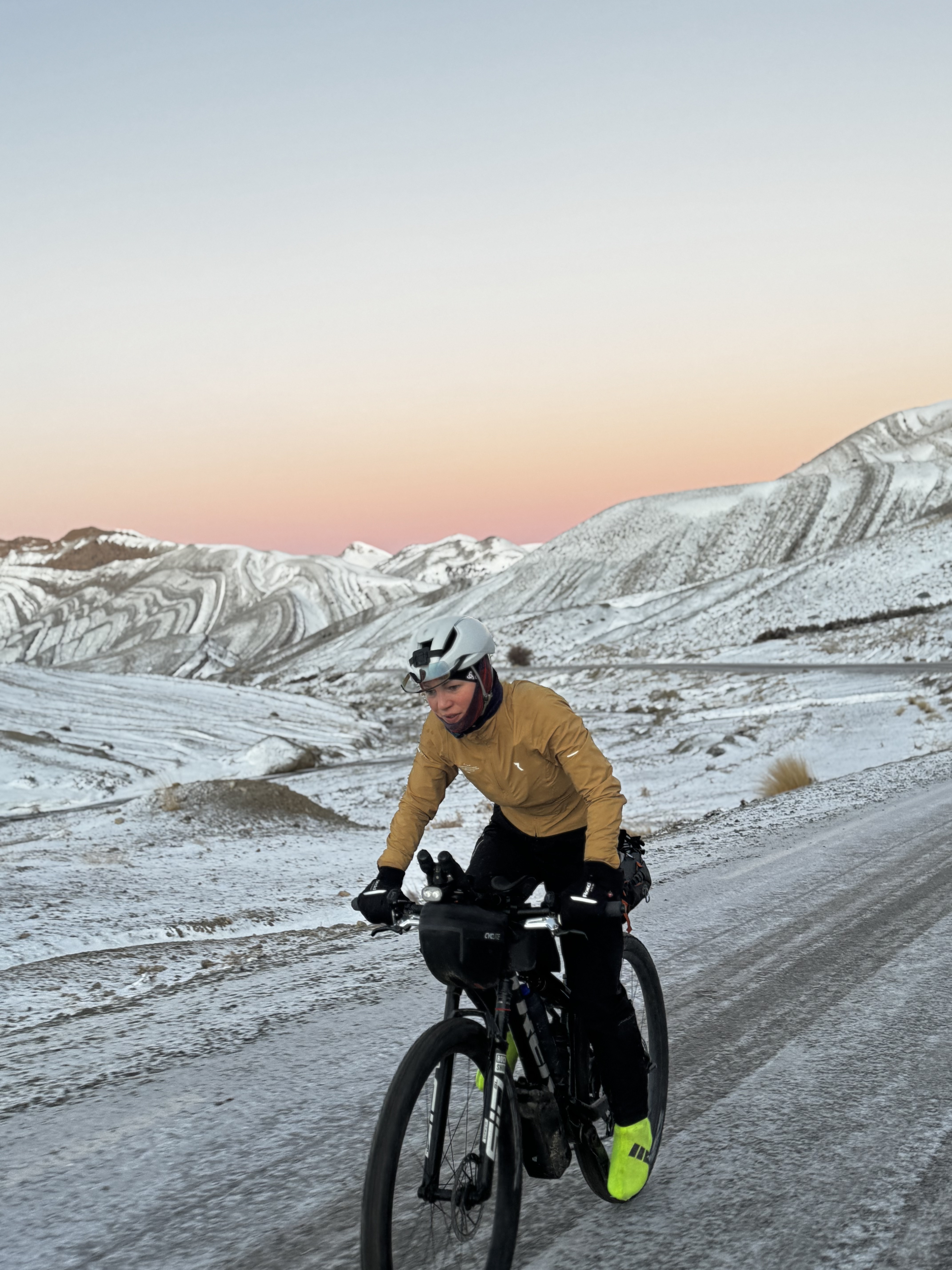 Jaqueline auf dem Bike in der verschneiten Berglandschaft des Atlas bei Sonnenaufgang