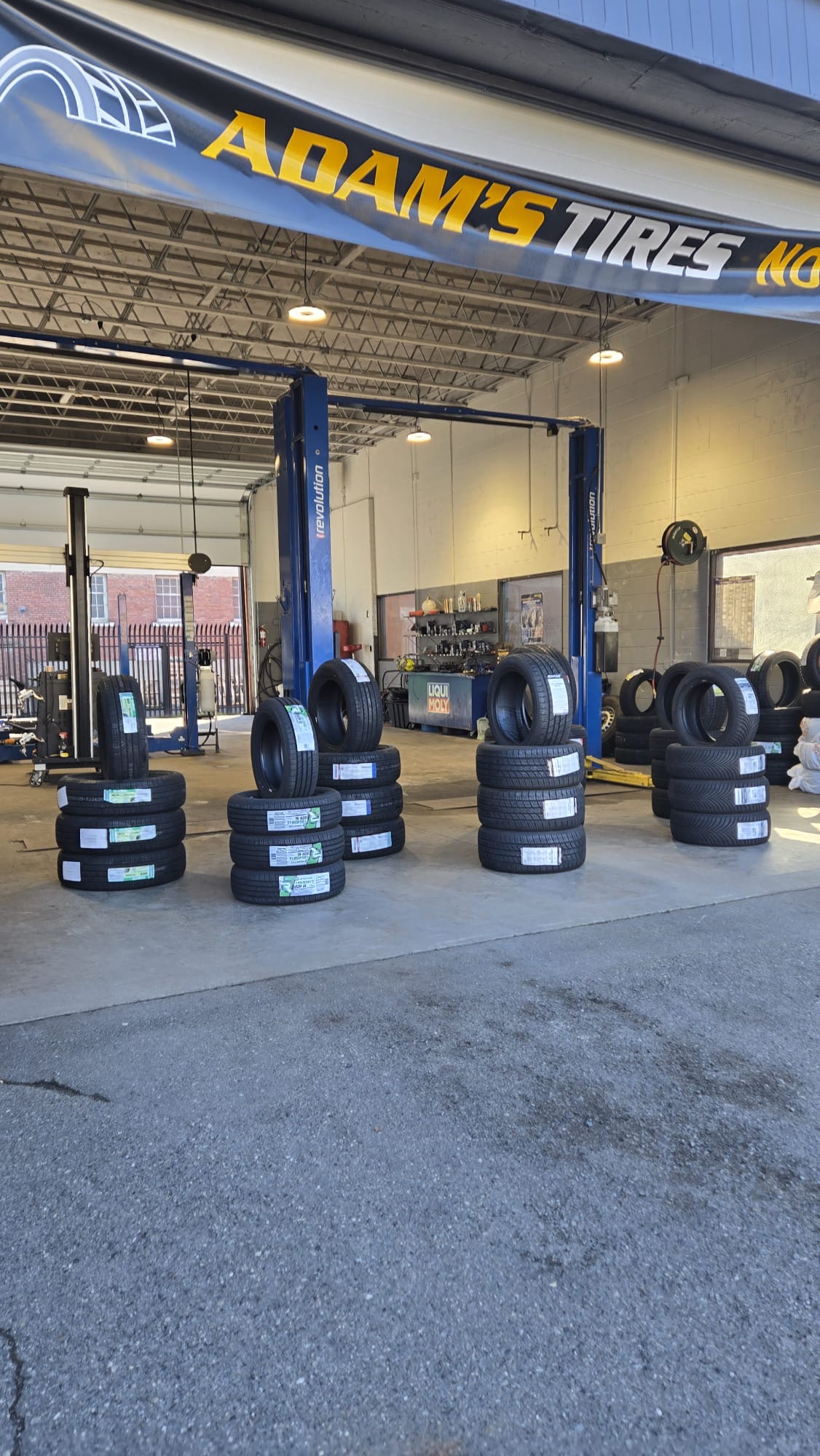 Adam's Tires storefront with stacks of tires on display