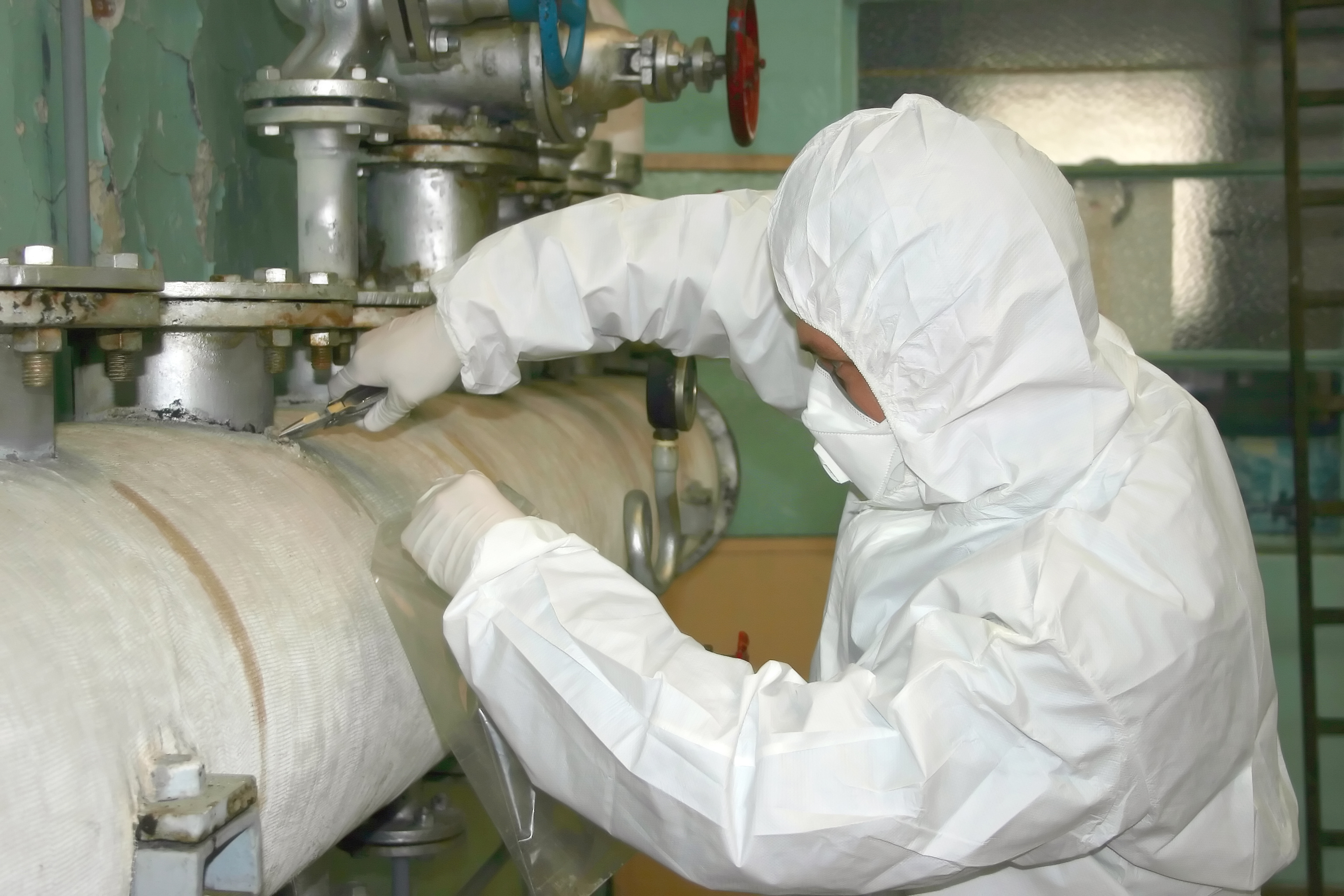 Arbeiter in Schutzkleidung bei Rohrisolierung