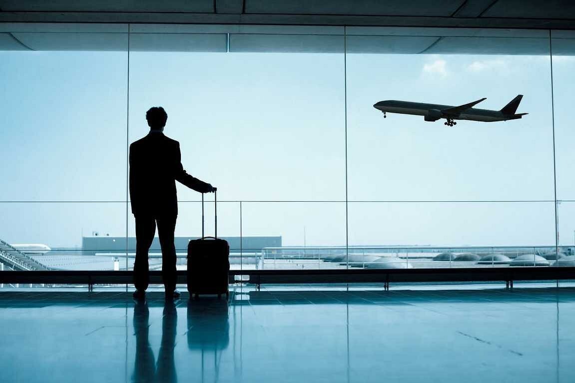 Businessman at airport window watching plane take off