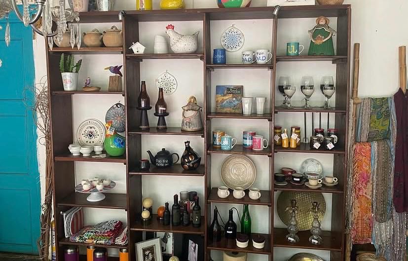 Estantería de madera con cerámica artesanal, tazas, copas, botellas y objetos decorativos de artesanos de Barichara en El Ángel Café