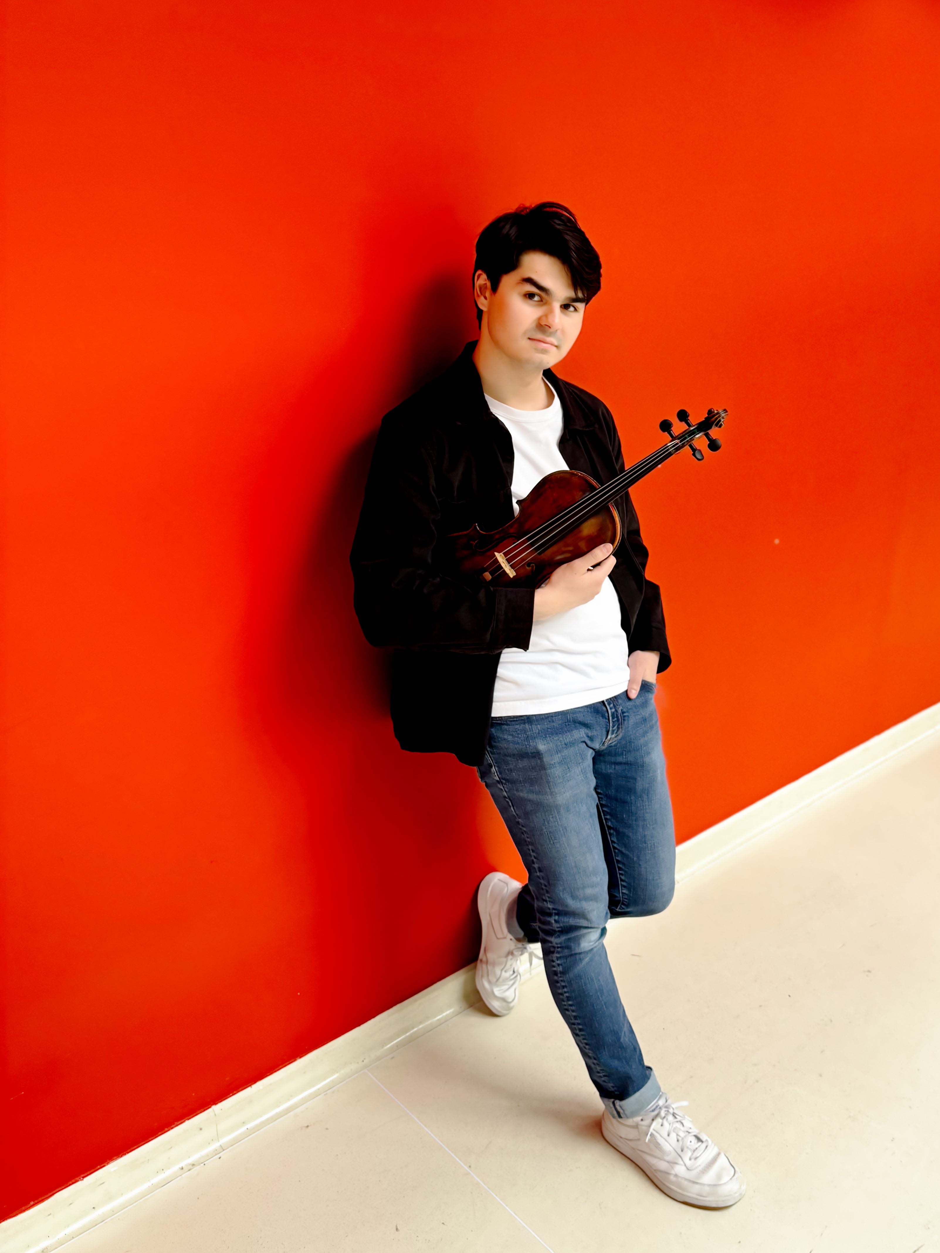Avery Scott against red wall with violin