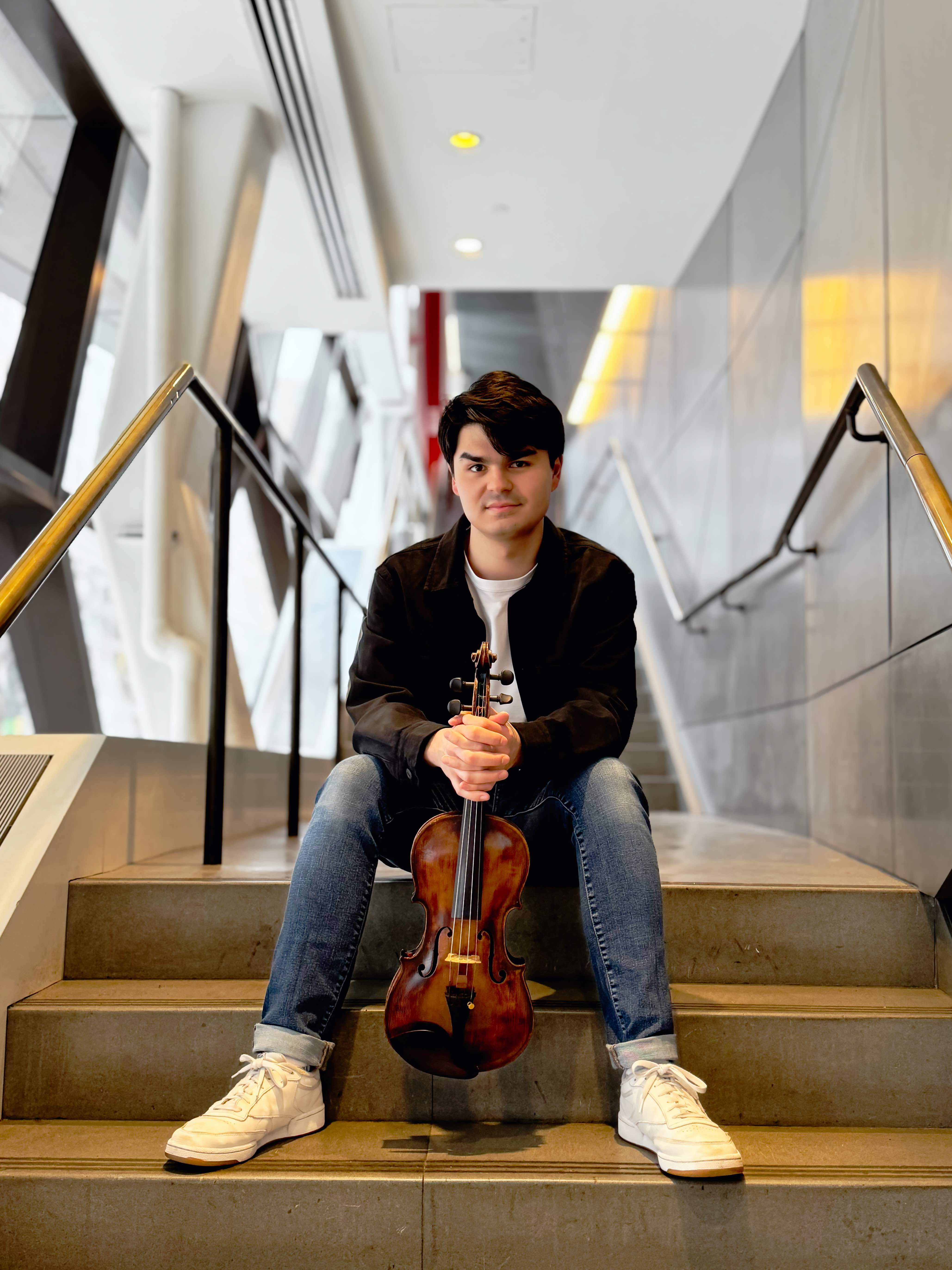 Avery Scott on stairs with violin between knees