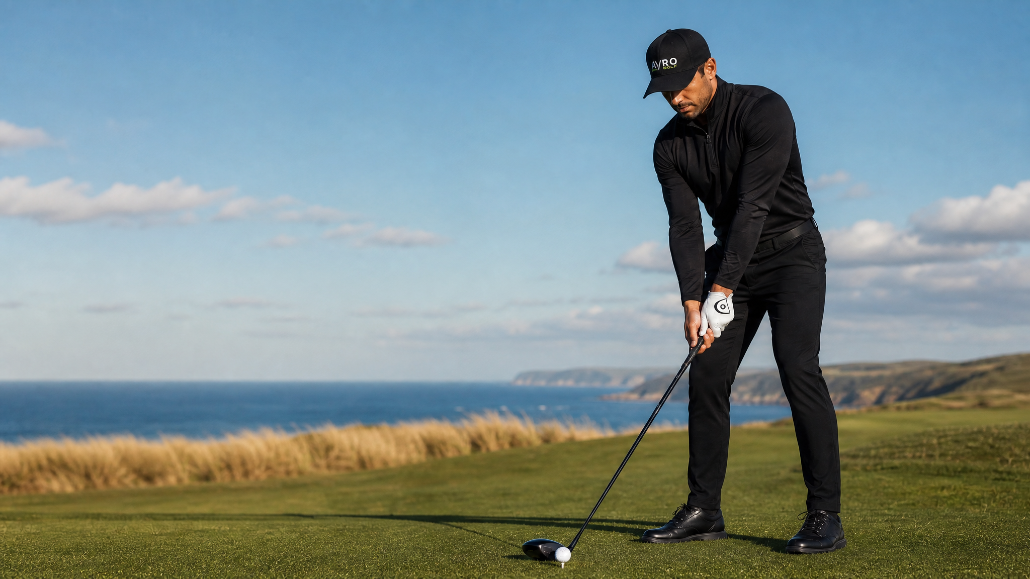 Golfer addressing the ball with a driver on a clifftop tee