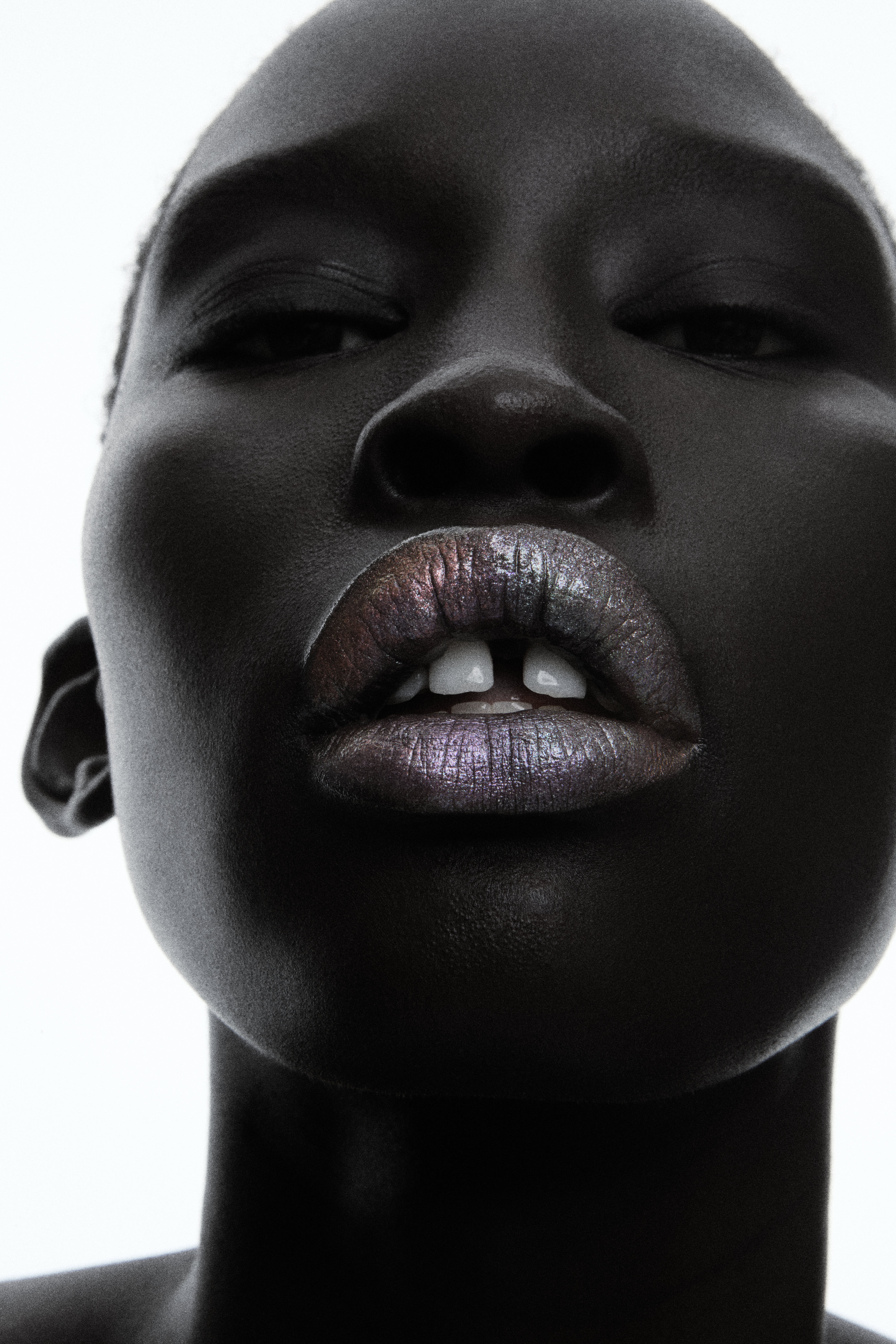 Beauty close-up of model tilted up with iridescent metallic lips against white