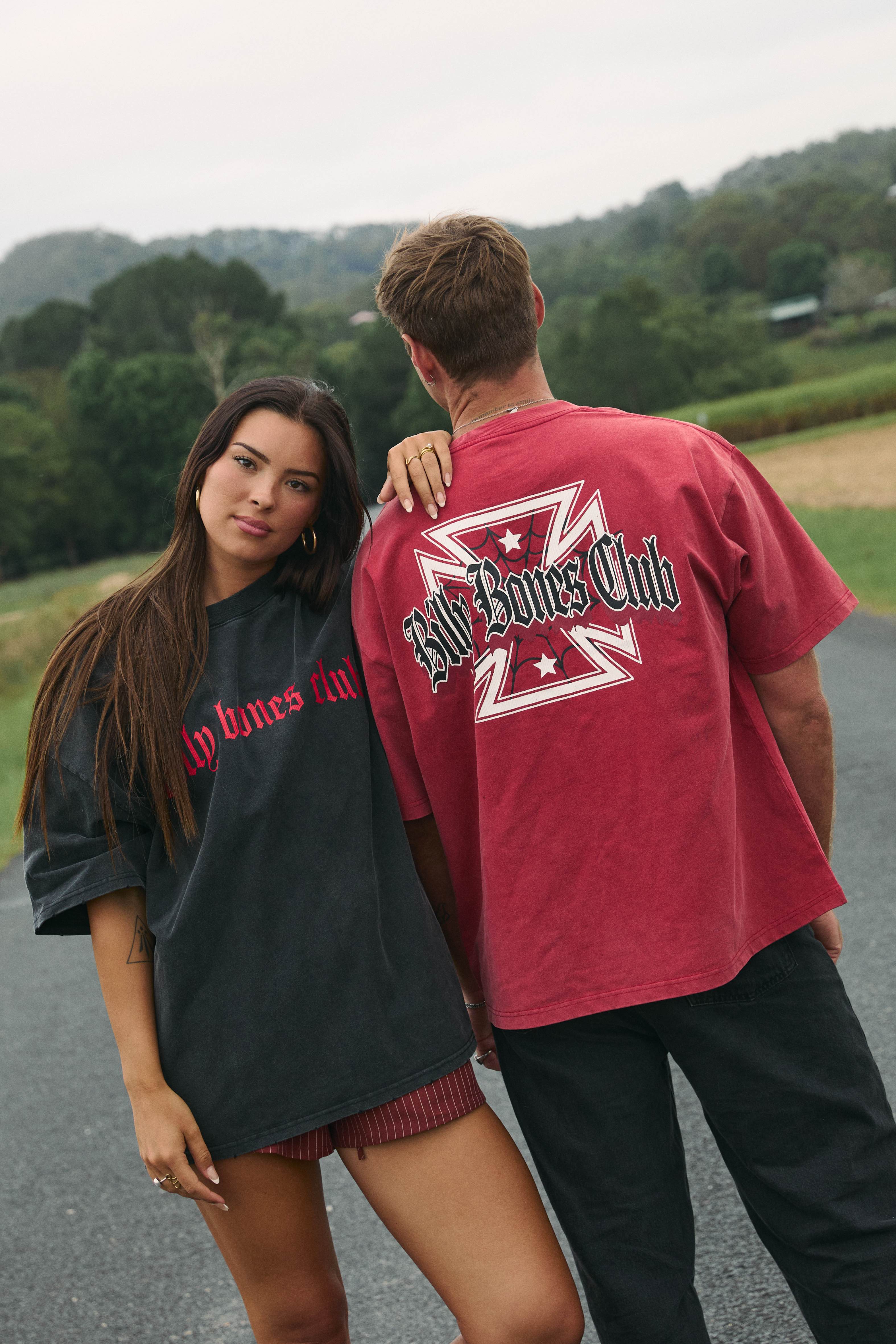 Couple in Billy Bones Club tees on a country road, streetwear campaign