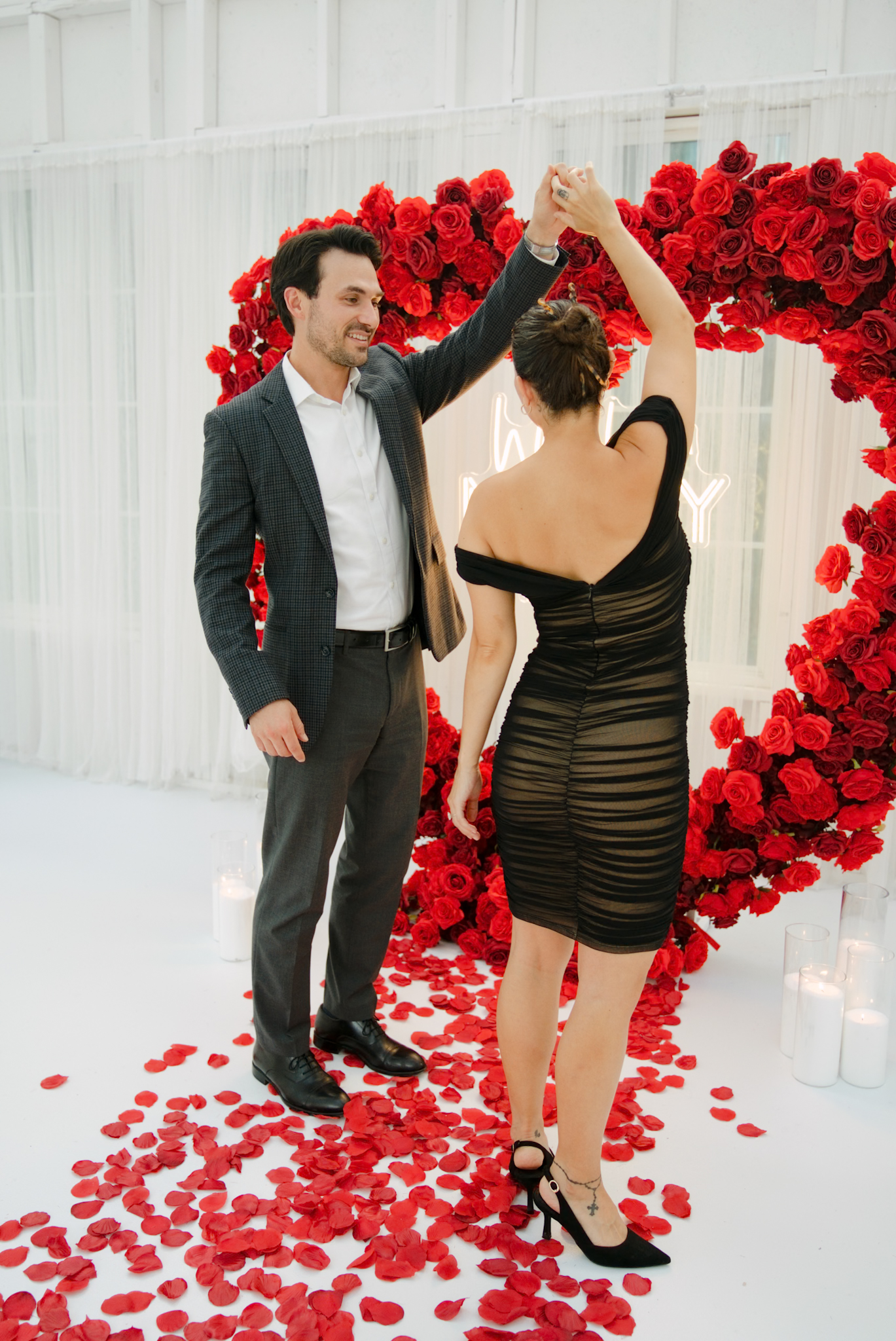 Partner twirling his fiancee among scattered rose petals