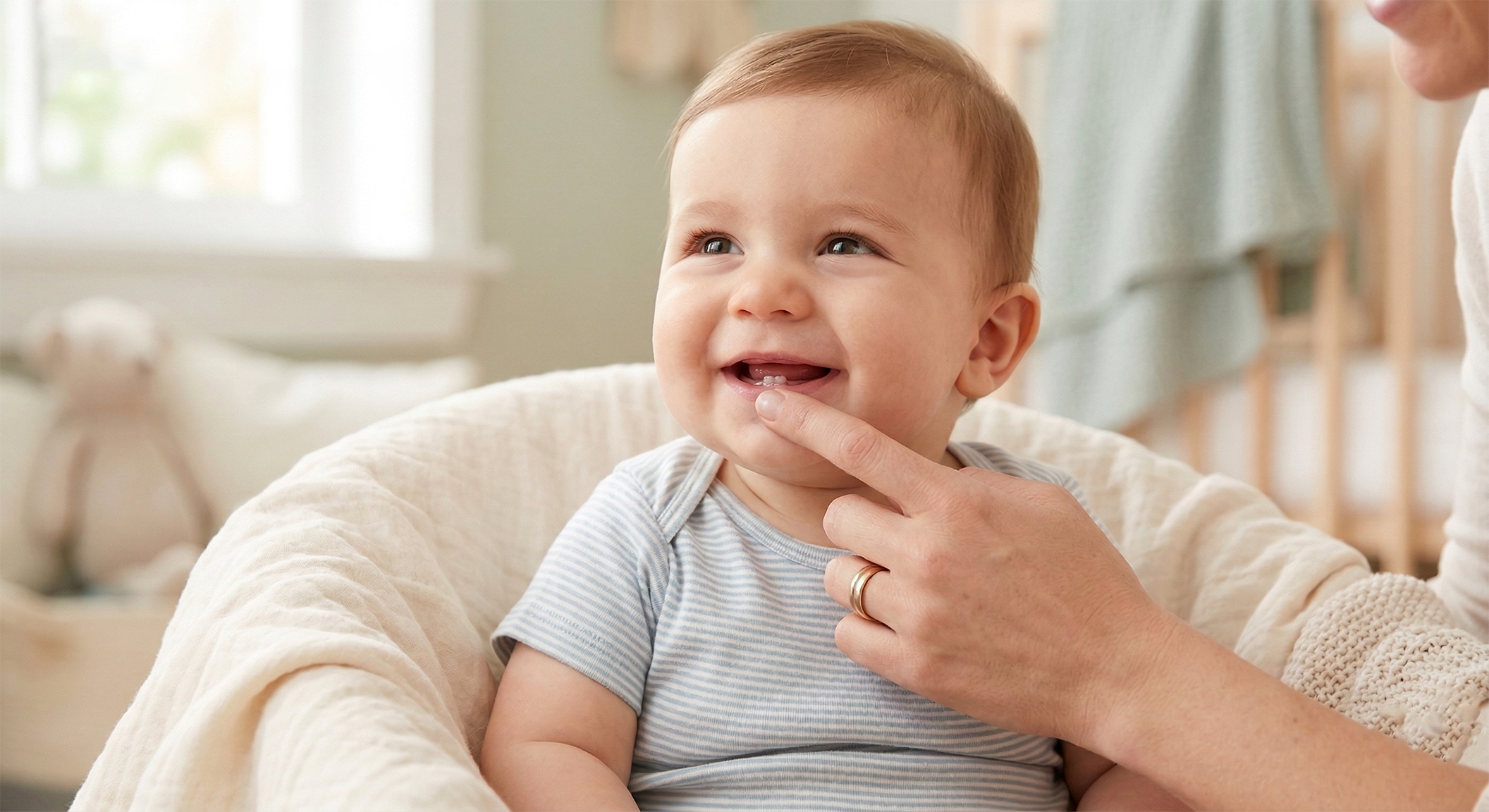 Happy baby smiling while parent applies teething gel