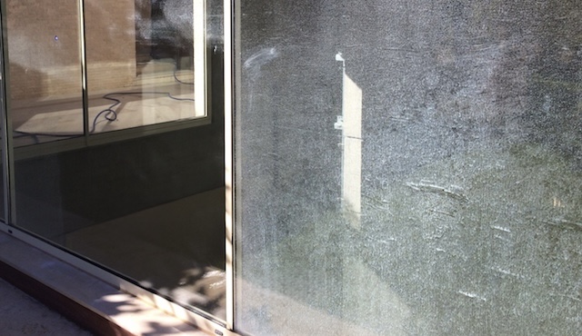 Side-by-side comparison: left half shows glass before treatment (contaminated with mineral deposits), right half shows the same glass after ClearShield treatment (clear)