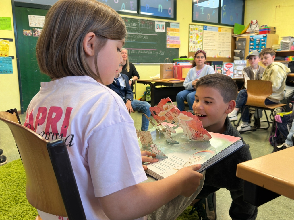 Kind zeigt einem anderen Kind ein aufgeklapptes Pop-up-Buch im Klassenzimmer