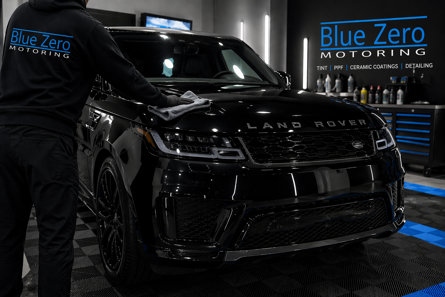 Blue Zero Motoring technician applying ceramic coating to a black Land Rover