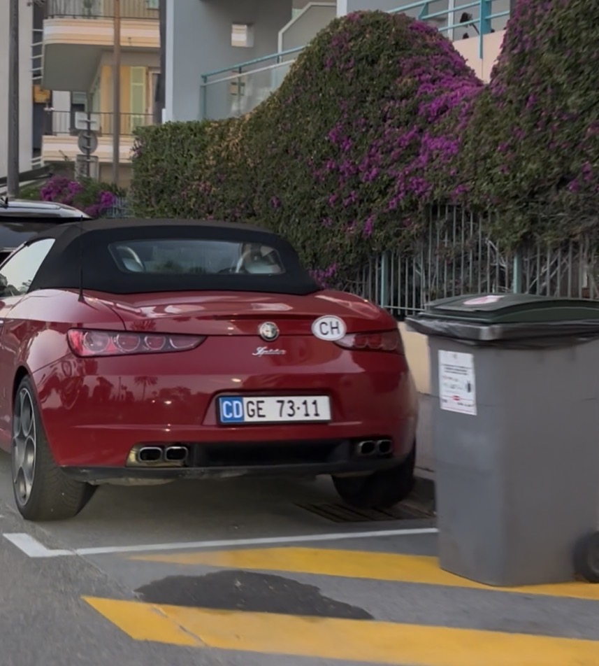 Plaque CD GE 73·11 — Mexique, corps diplomatique, Genève Plaque diplomatique suisse CD GE 73·11 sur une Alfa Romeo Spider cabriolet rouge garée dans un parking ensoleillé à Genève — code 11 correspondant au Mexique, canton GE (Genève), statut CD, numéro de série 73