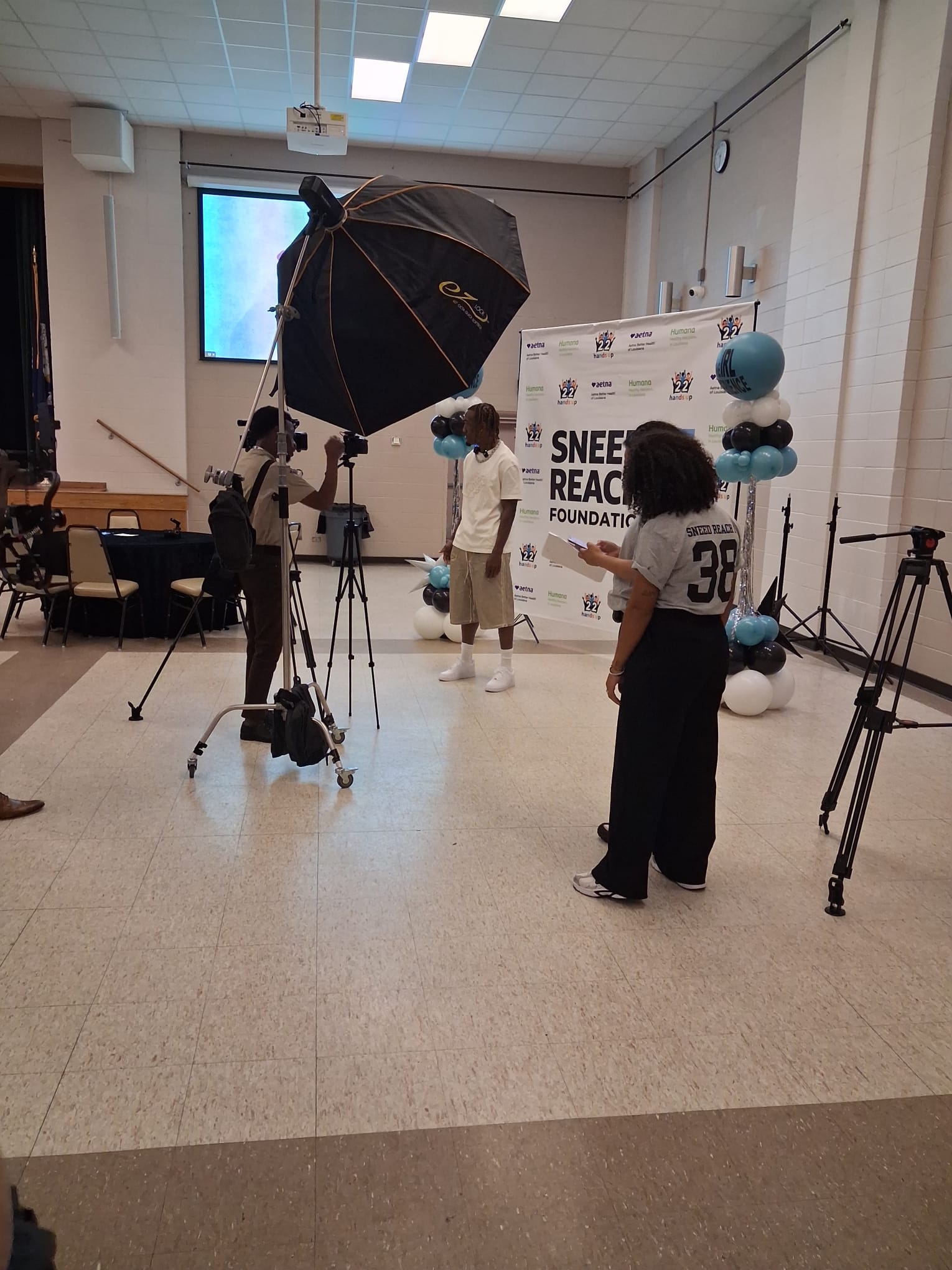 L'Jarius Sneed being interviewed by media in front of the Sneed Reach Foundation backdrop