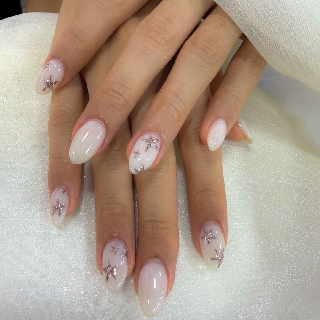 Milky white gel nails with silver glitter star designs by Colour Workshop Singapore