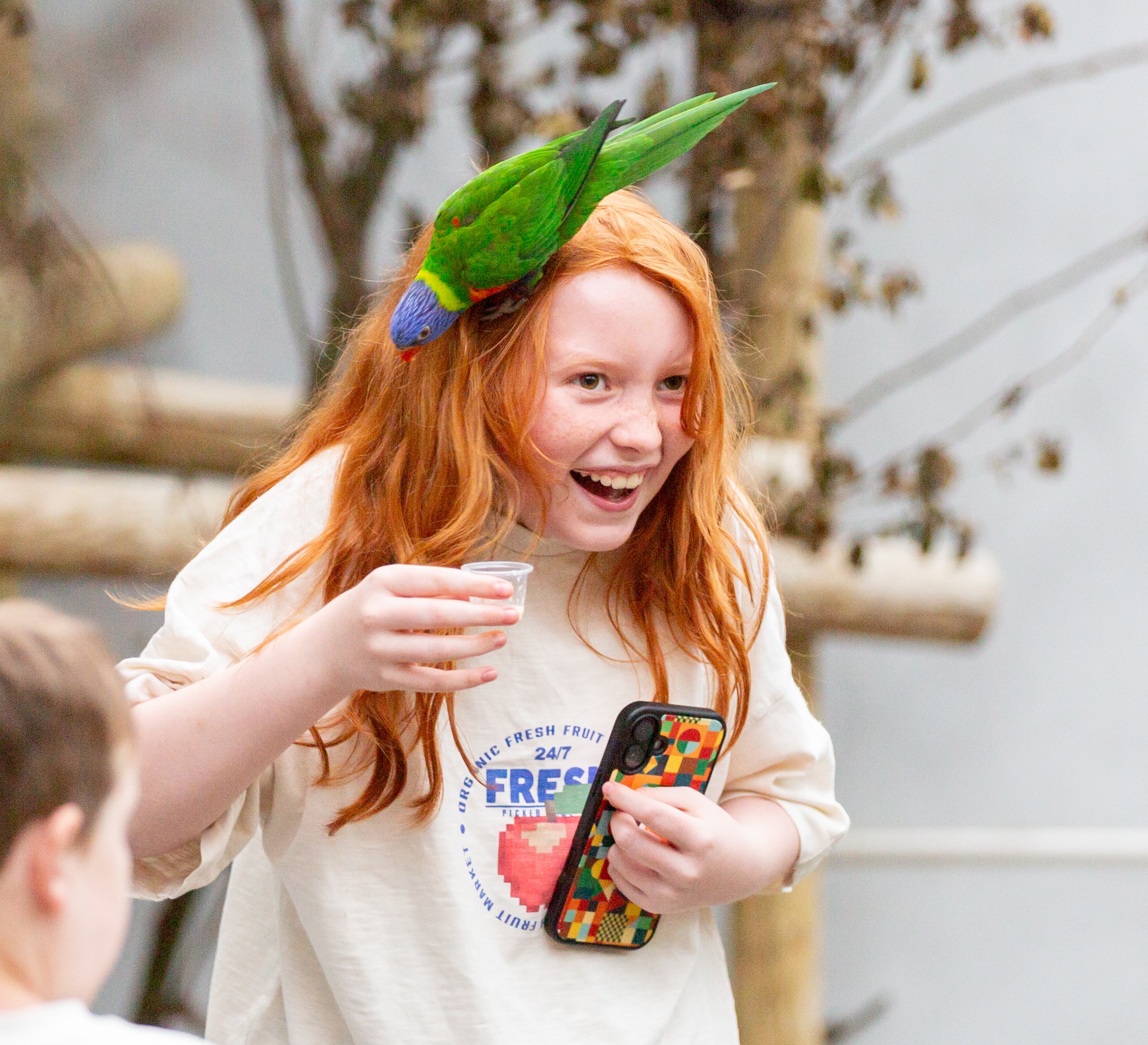 Teenage girl with a parrot sitting on her head, laughing at a SEND Fest event