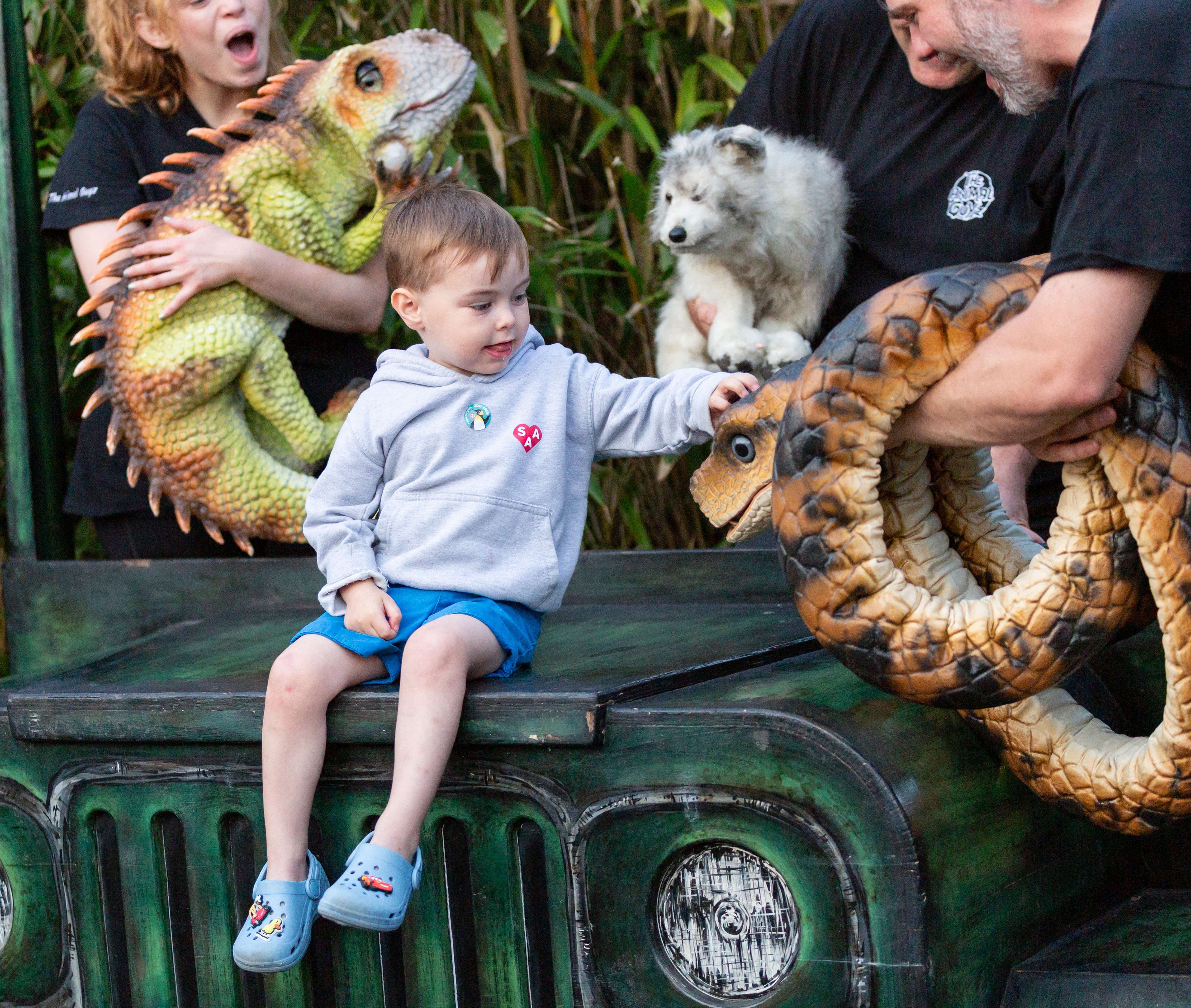 Young child reaching out to touch a dinosaur puppet at SEND Fest