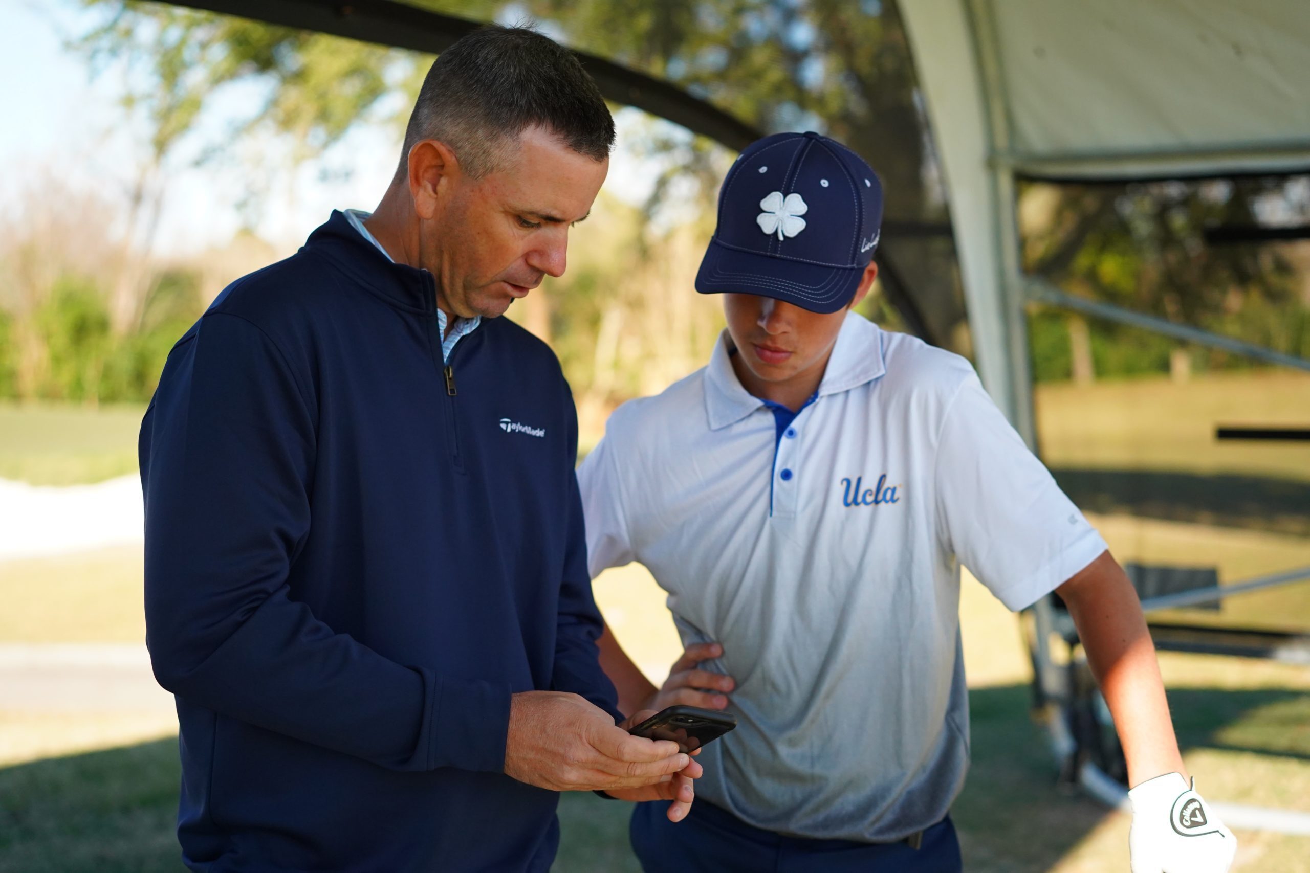 Coach mentoring a UCLA golfer at the golf course