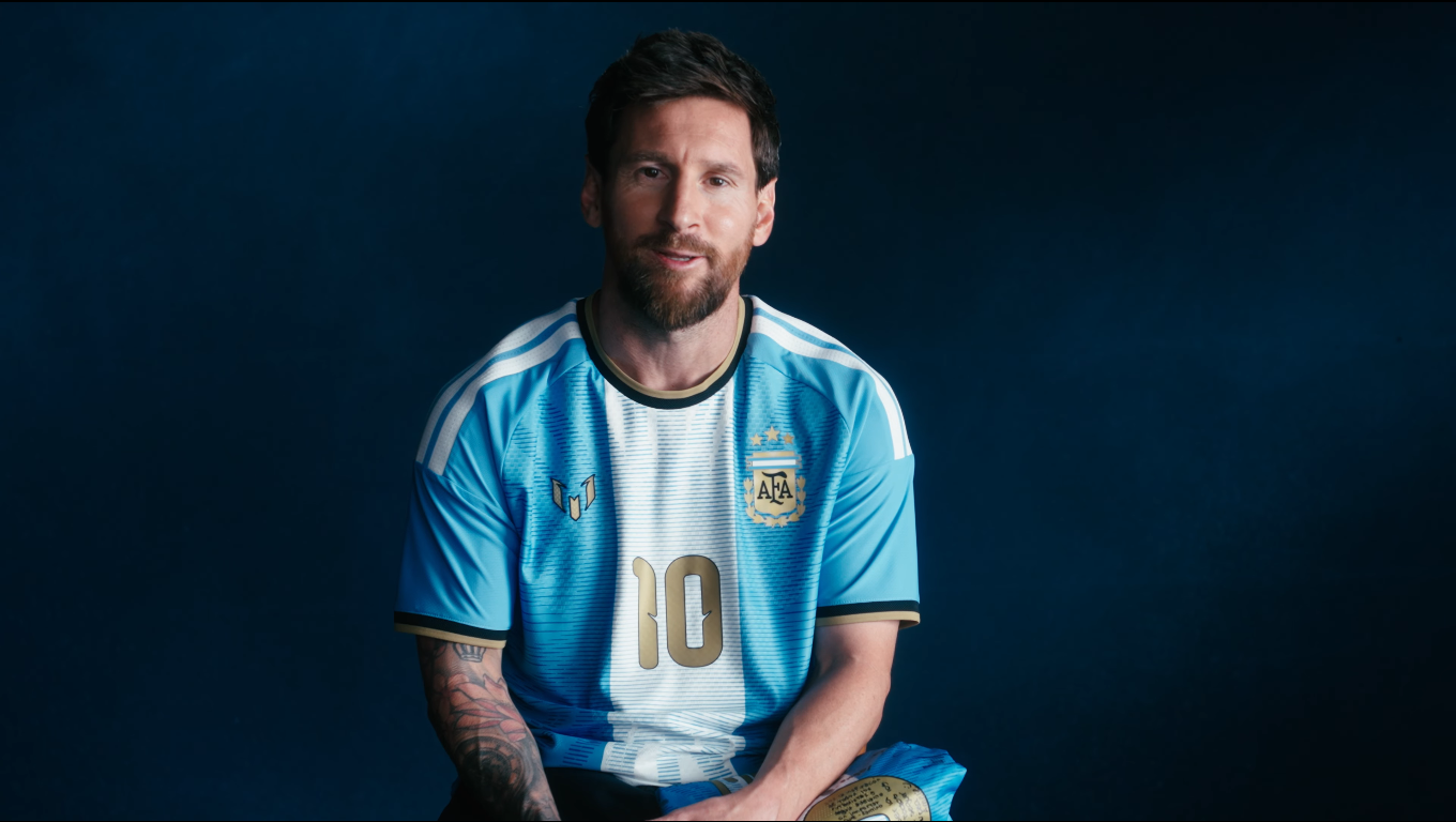 Messi sentado con la camiseta argentina y una pelota