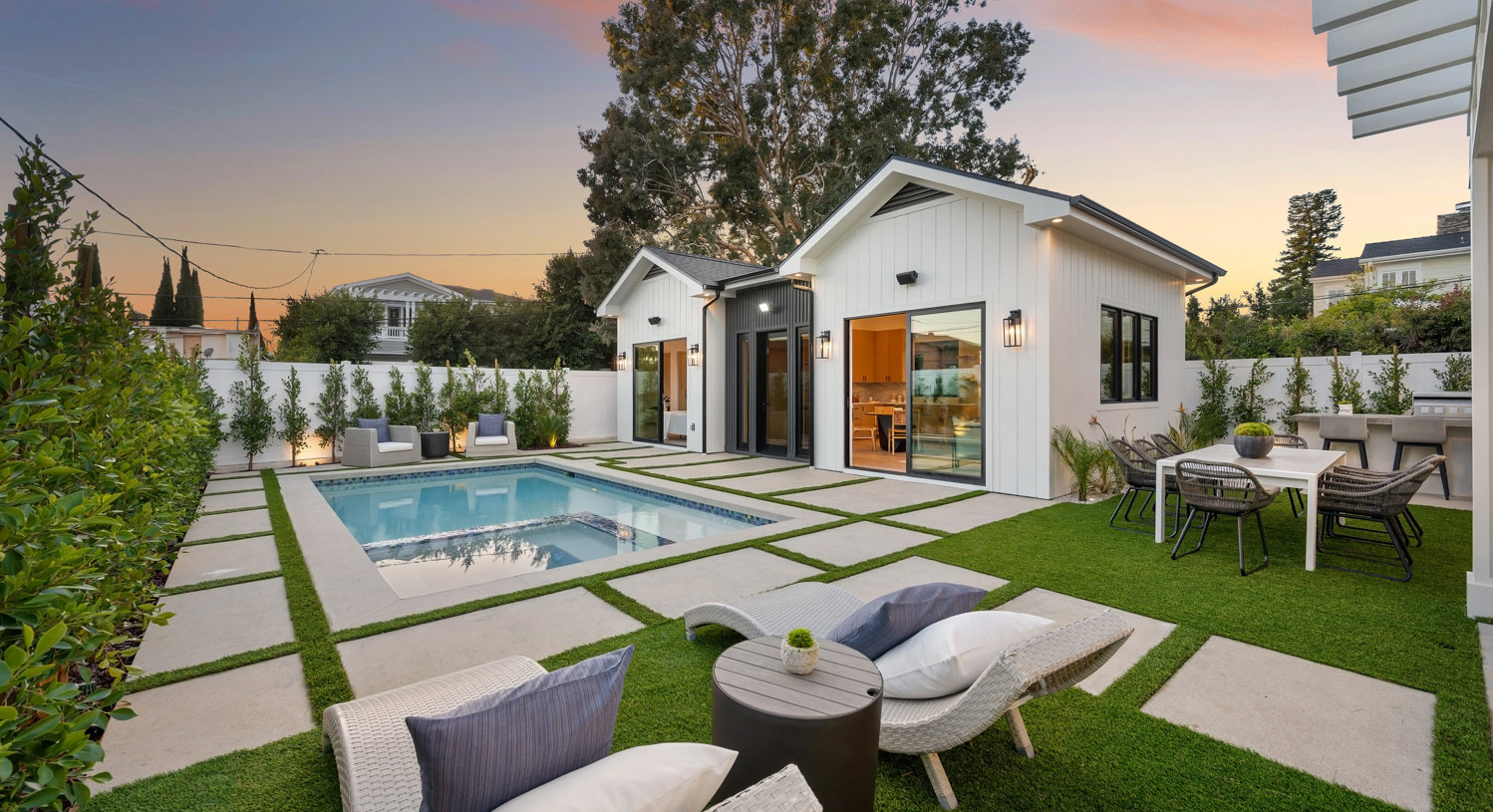 Beautiful white farmhouse-style ADU with pool at sunset
