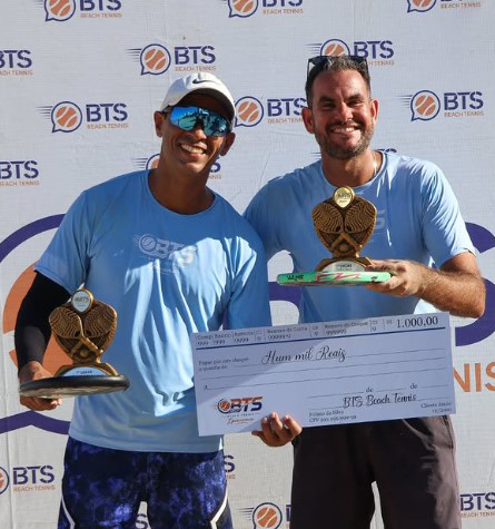 Dupla comemorando com troféus e cheque
