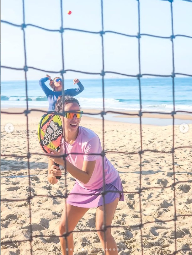 Jogadora de Beach Tennis atrás da rede com o mar ao fundo