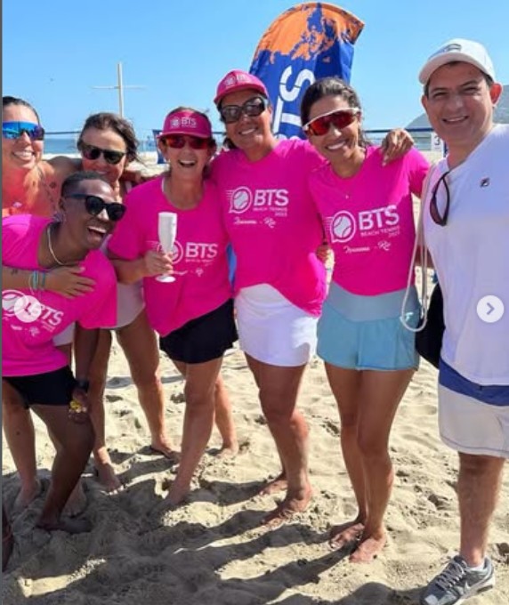 Grupo de participantes usando camisetas rosas na praia
