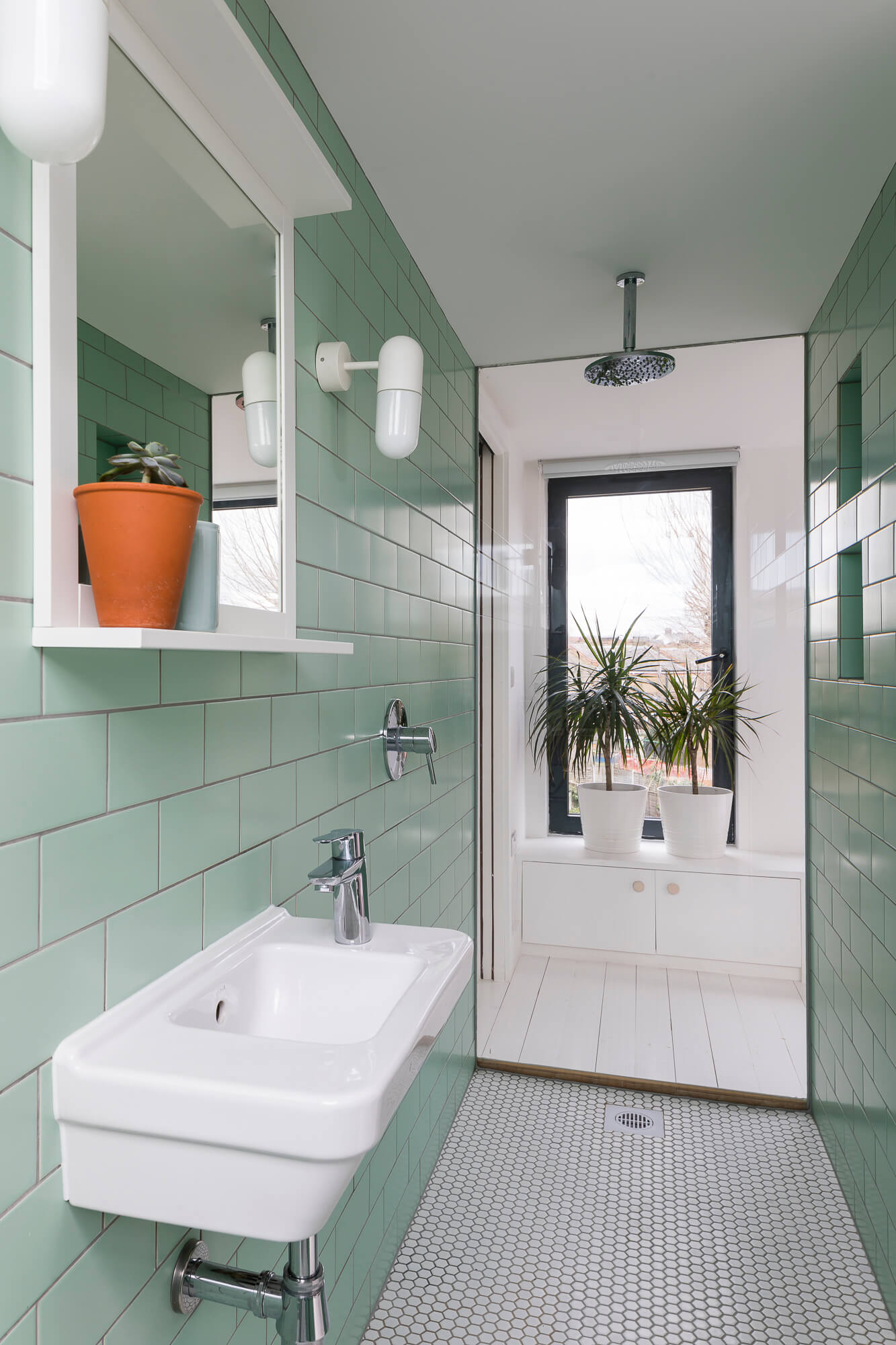 Bathroom with mint green subway tiles, white penny round floor tiles, and floating sink