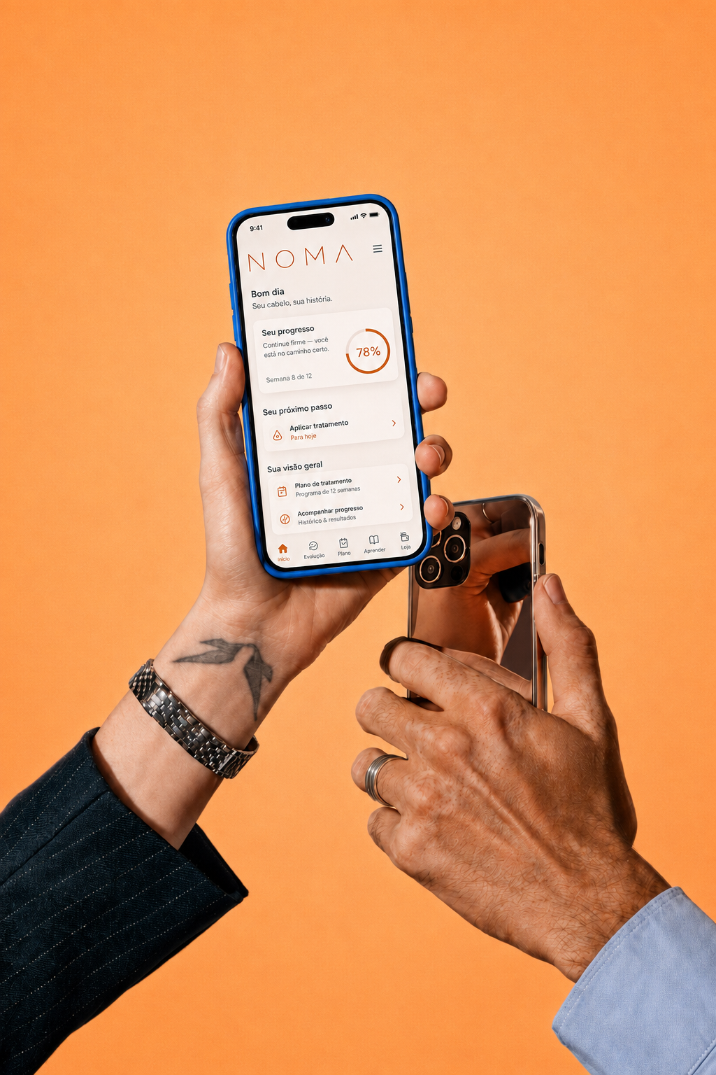 Mãos segurando smartphones com o aplicativo NOMA diante de um fundo laranja