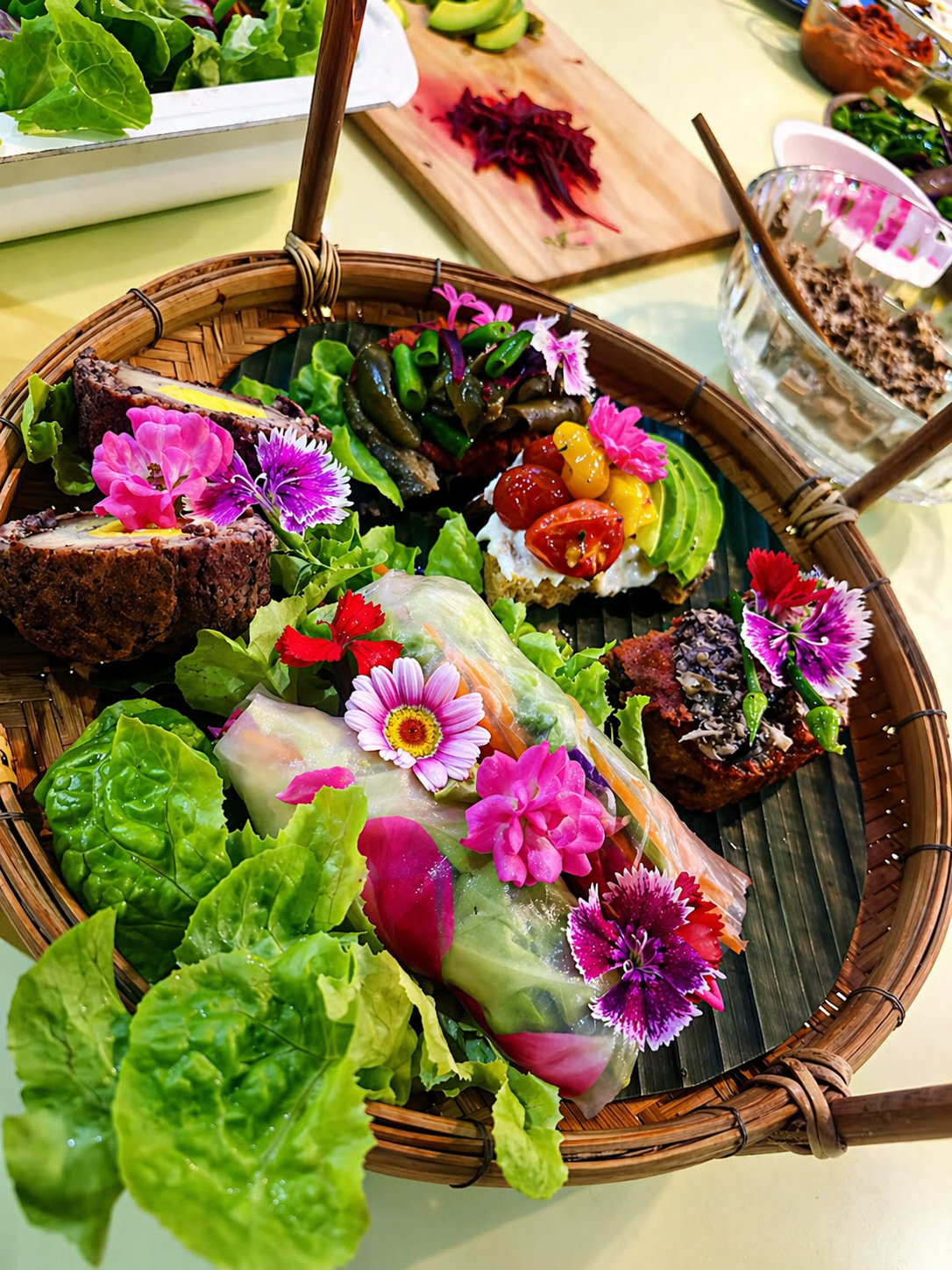 Bamboo basket with colorful spring rolls and fresh flowers