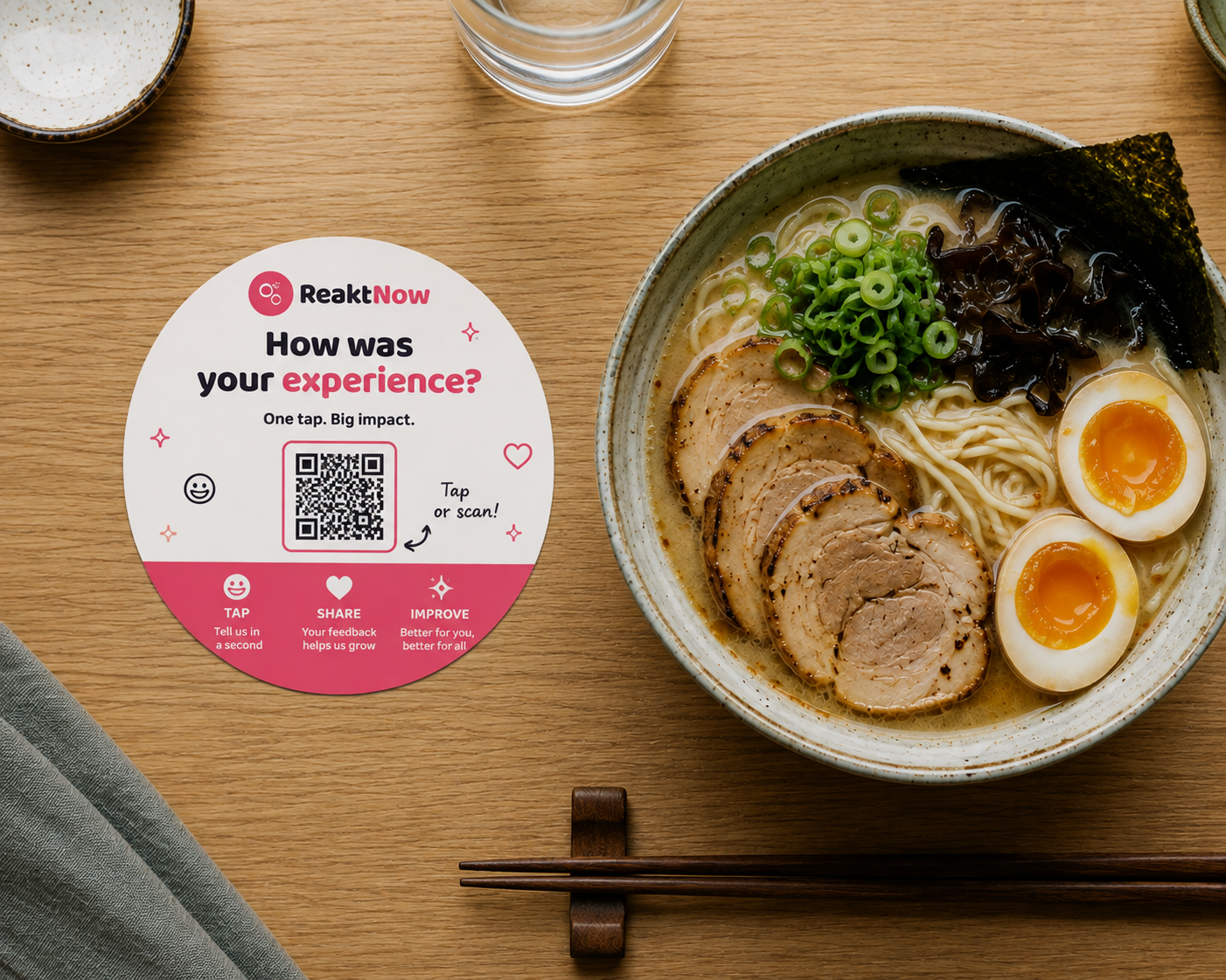 A round ReaktNow table placard next to a bowl of ramen