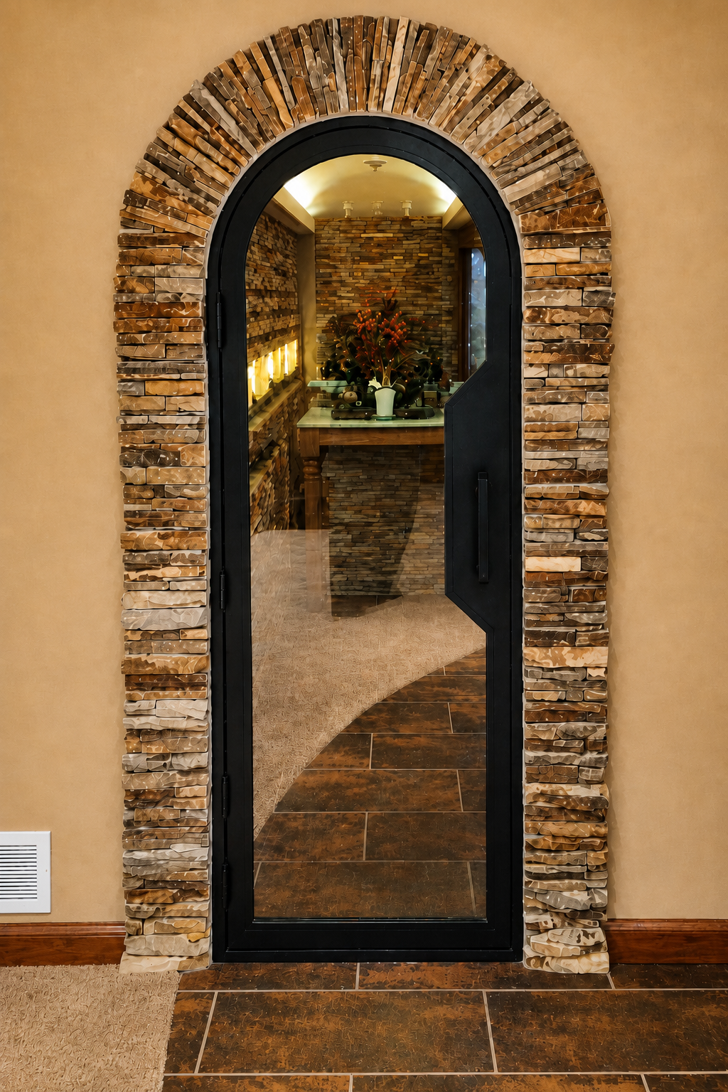 Custom stone archway featuring hand-laid ledger stone in warm tan and brown tones framing a tall arched black glass door.