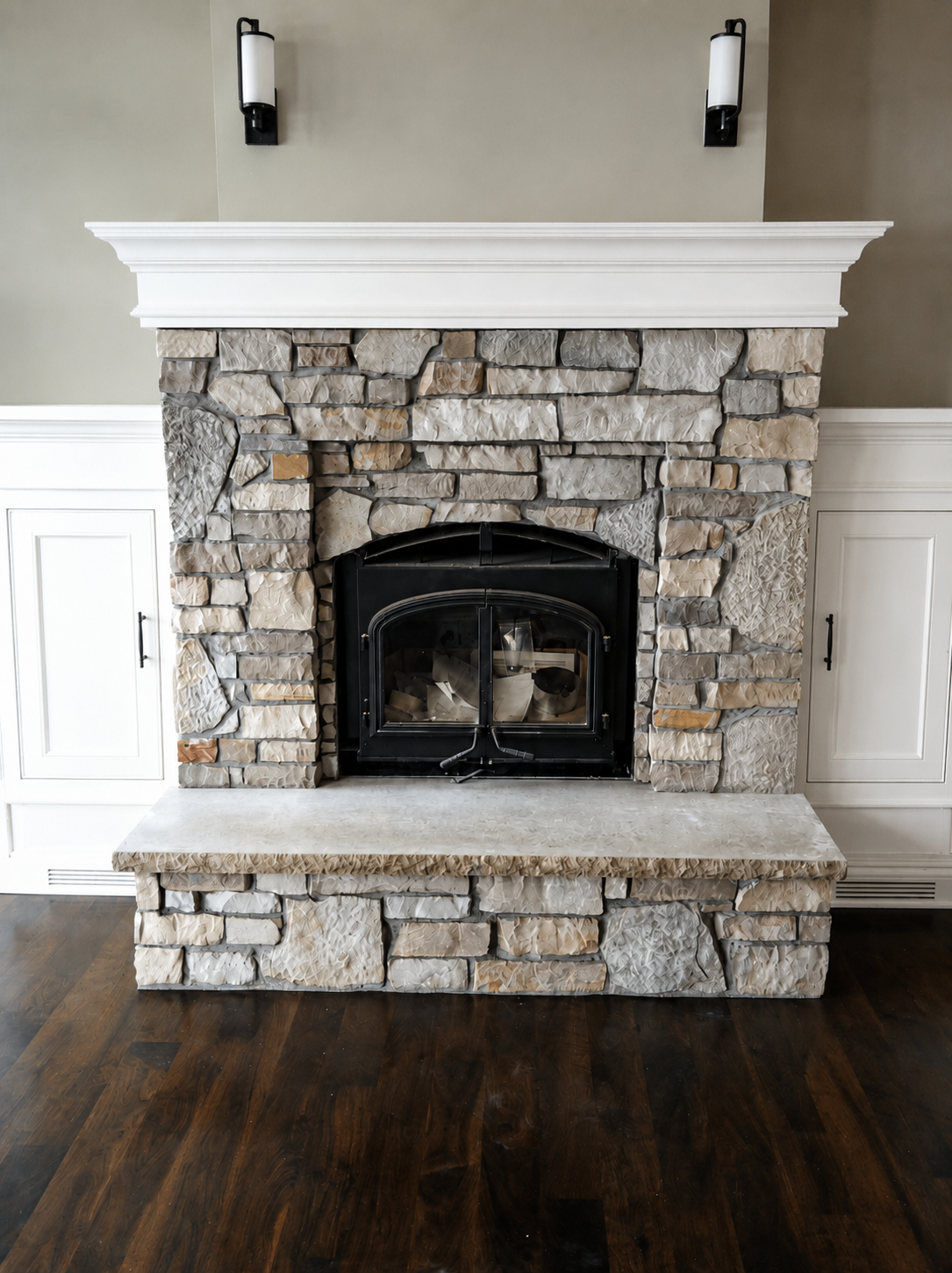 Custom stone fireplace featuring expertly coursed tan and gray masonry with a black wood-burning stove insert and white mantel.