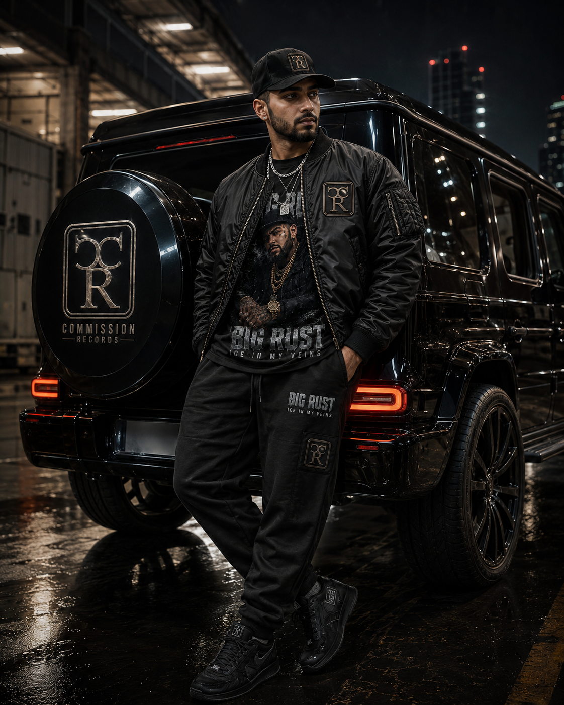Man leaning against a black G-Wagon in a rainy industrial lot at night, wearing a black Big Rust Ice In My Veins portrait graphic tee under a black CR bomber jacket with CR patches, matching black Big Rust Ice In My Veins CR joggers, a black-and-gold CR snapback, and black CR sneakers