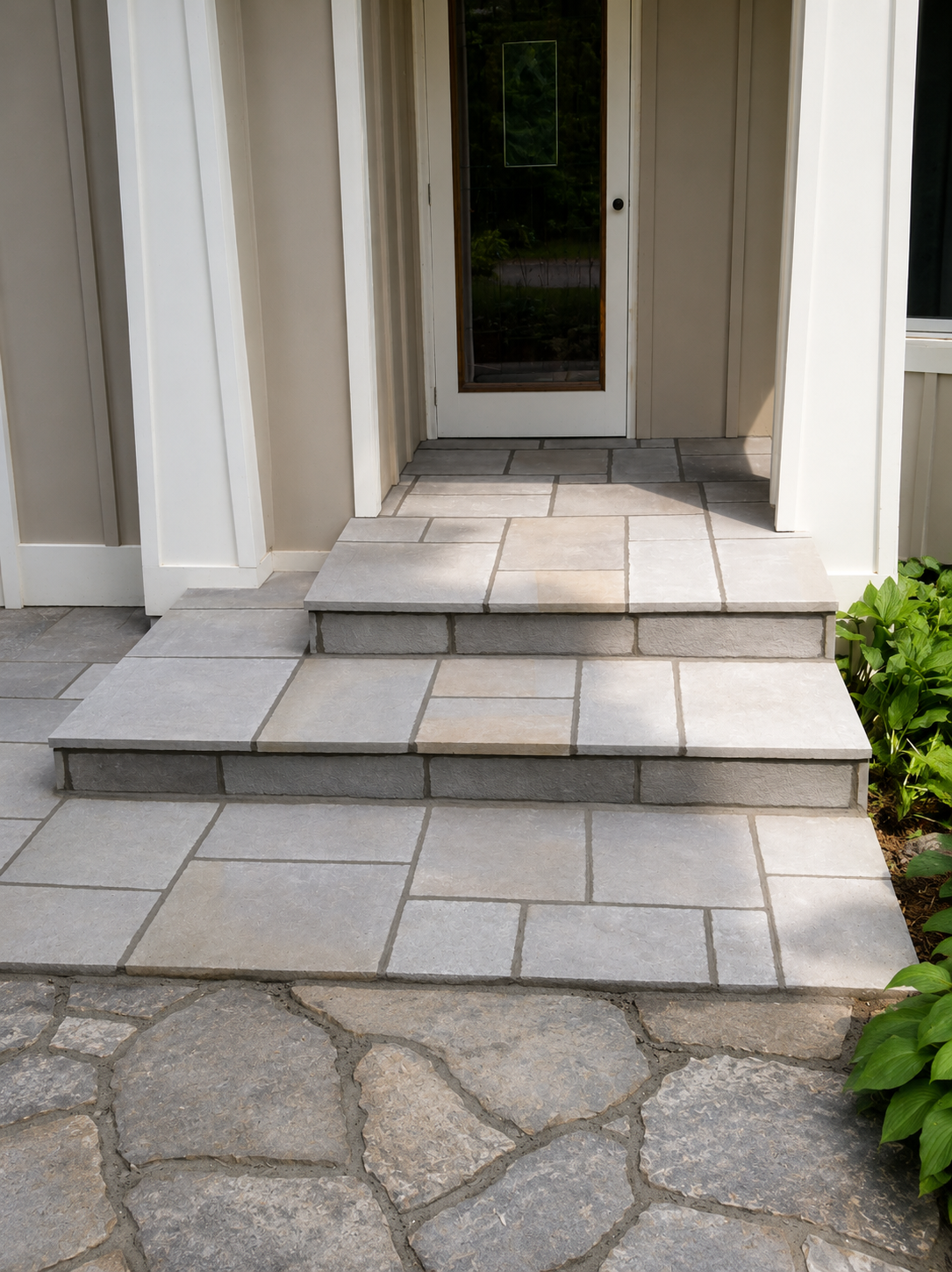 Precisely laid stone entry steps and paver landing leading to a white-trimmed residential front door.